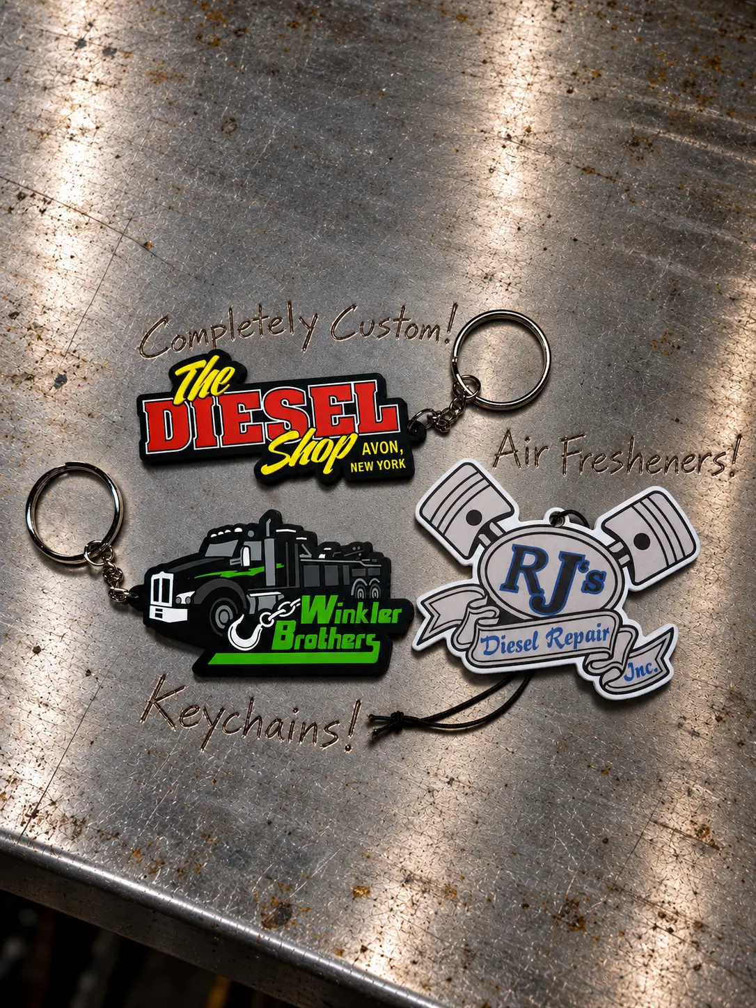 Custom keychains and an air freshener with full-color shop logos, on a workbench.